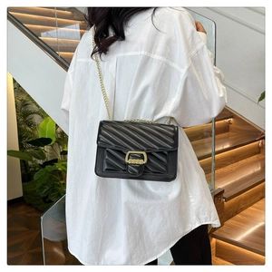 Close-up of black quilted crossbody bag featuring V-shaped stitching and gold chain strap