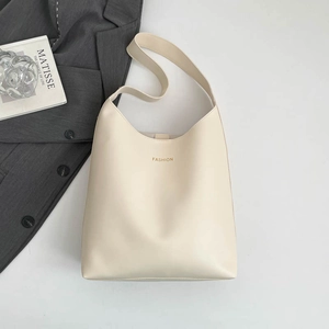 Minimalist off-white leather tote bag with gold fashion text and wide shoulder strap
