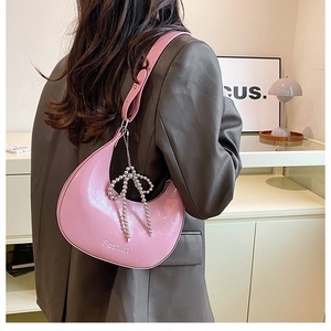 Detail of pink patent leather hobo bag with Fashion text and silver beaded bow charm