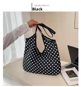 Detail of black canvas tote bag with white polka dot pattern and sturdy handles