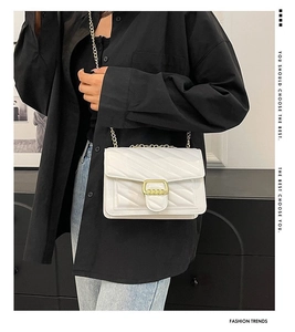 Detail of white chain crossbody bag with V-shaped stitching and golden square clasp