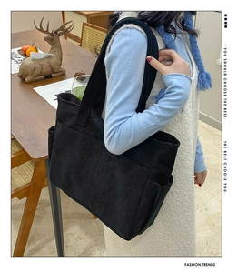Close-up of black corduroy tote bag featuring two side pockets for daily essentials