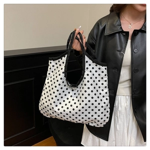 Detailed close-up of a white canvas tote bag with black polka dots and black handles