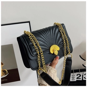 Detailed close-up of the shell-shaped gold clasp and quilted embroidery on the black bag