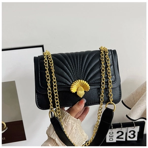 Detailed view of black quilted crossbody bag with fan-shaped gold clasp and chain strap