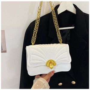 Detail of white quilted crossbody bag featuring a golden fan-shaped buckle and chain strap