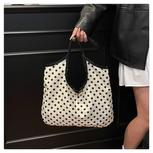 Detail of large polka dot canvas tote bag showing black wide webbing handle and finish