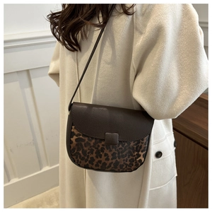 Detail of retro saddle bag featuring brown lychee leather and leopard print patchwork texture