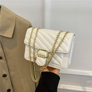 Elegant white quilted crossbody bag with gold buckle and chain strap shown in a lifestyle view