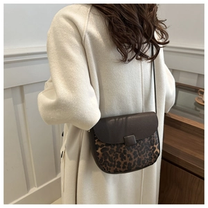 Detail of a vintage leopard print saddle bag with textured brown leather flap for women