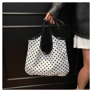 Detailed view of white canvas tote bag with black polka dots and durable black handles