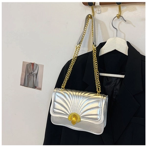 Detail of silver quilted handbag with fan pattern stitching and golden chain strap