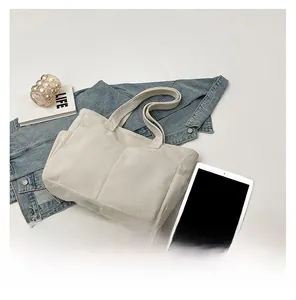 Detail of cream corduroy tote bag featuring side pockets and textured vertical ribs