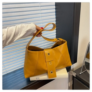 Detail of vintage mustard yellow PU leather handbag with metal eyelets and strap buckle
