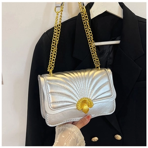 Close-up of silver quilted crossbody bag featuring a golden shell-shaped metal lock detail