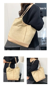 Detail of a large beige tote bag featuring a decorative bow tie and stylish leather bottom