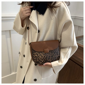 Detail shot of a brown saddle bag featuring leopard print texture and metal buckle