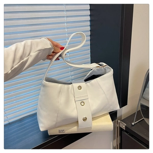 Detail of white pleated leather handbag with golden metal eyelets and wide shoulder strap