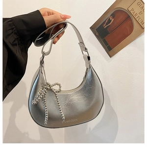 Detail view of silver moon bag with metallic texture and beaded butterfly pendant charm