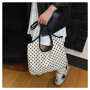 Detailed view of large capacity white polka dot canvas tote bag with black edge trim straps