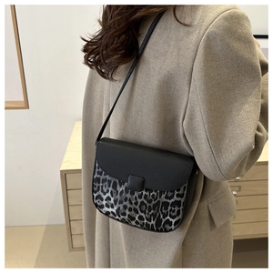 Detail view of leopard print saddle bag with black lychee grain leather and shoulder strap