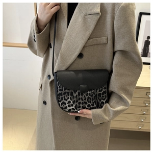 Close-up of contrast saddle bag with leopard print and black lychee grain texture