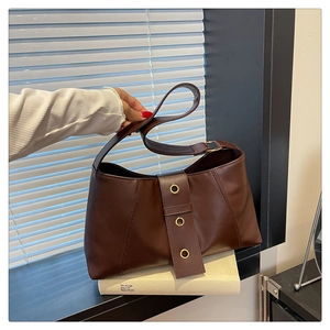 Detail view of dark brown faux leather shoulder bag with gold metal eyelet accents and strap