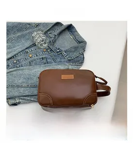 Detail of brown vintage leather makeup bag with white double stitching and gold zipper
