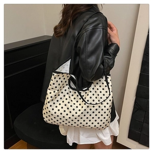 Detailed shoulder view of a large polka dot canvas tote bag with black reinforced handles