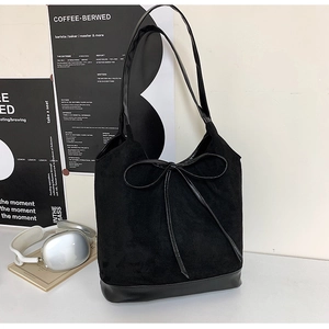 Detail of black suede tote bag with slim bow knot and sleek leather shoulder strap