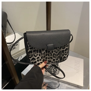 Detail of saddle bag with black lychee leather flap and leopard print pattern