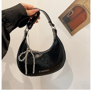 Detail of black pleated faux leather underarm bag with silver beaded bow charm and zipper