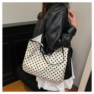 Detailed side view of large white canvas tote bag with black polka dots and shoulder straps