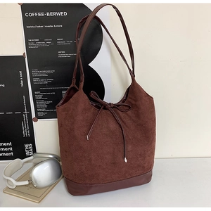 Detail of dark brown tote bag featuring suede fabric panels and smooth leather handles