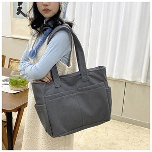 Detail of grey corduroy tote bag showing thick ribbed texture and functional side pockets
