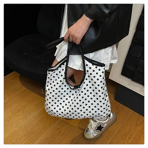 Close-up of minimalist black and white polka dot canvas tote bag with black strap handles