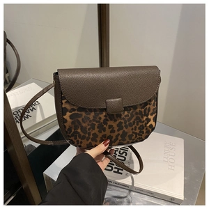 Detailed view of saddle bag showing brown lychee leather and leopard print texture