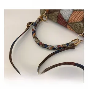 Detail of multi-textured patchwork leather bag with woven handle and gold hardware