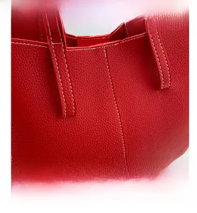 Macro shot of red lychee grain leather tote bag featuring white contrast stitching details