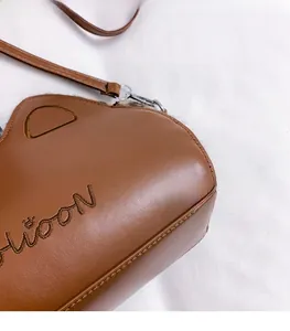Gros plan détaillé du sac bandoulière en cuir marron avec broderie Moon et anneau D