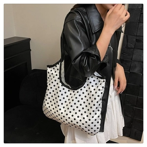 Detail view of large white canvas tote bag with black polka dots and reinforced edges