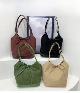 Detail view of suede tote bags in burgundy black green and beige with bow accents