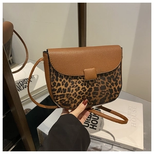 Detail view of saddle bag showing brown lychee leather texture and leopard print body