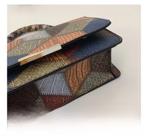 Close-up of geometric patchwork leather textures and golden magnetic buckle on handbag