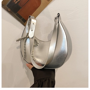 Close-up of silver metallic hobo bag featuring a beaded chain and embossed fashion text