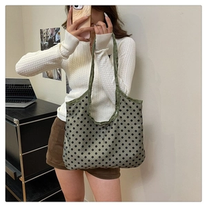 Detailed side view of a large olive green tote bag with black polka dots on the shoulder