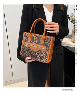 Close-up of leopard print tote bag with brown leather handles and golden zipper detail