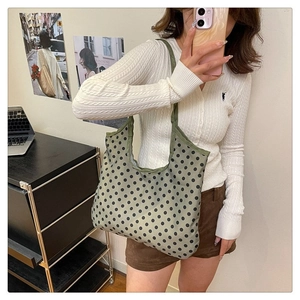 Detail of green canvas tote bag with black polka dots and wide shoulder straps