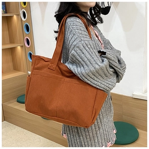Detail of caramel corduroy tote bag showing ribbed texture and side pocket on a model
