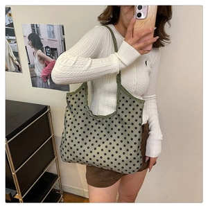 Army green canvas tote bag with black polka dots shown on model in a casual setting
